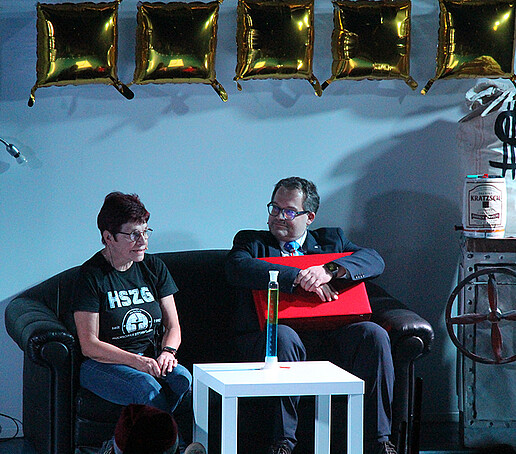 Frau Hollstein und der Rektor sitzen auf der Couch.