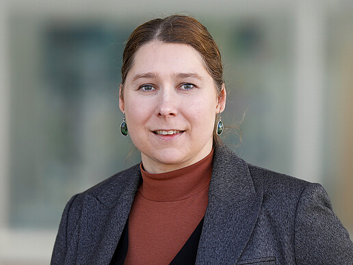Prof. Dr. rer. nat. Elisa Wirthgen steht vor einem Gebäude und lächelt in die Kamera.