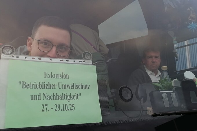 Im Bus hält ein Mitfahrer ein Reiseschild in die Frontscheibe.