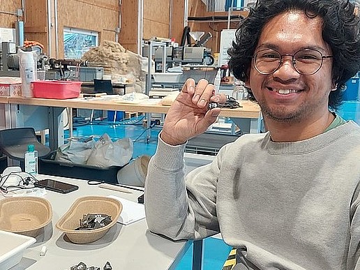 Faiz sitzt im Lander Technikum am Arbeitsplatz. vor ihm liegen schwarze Kunststoffteile.