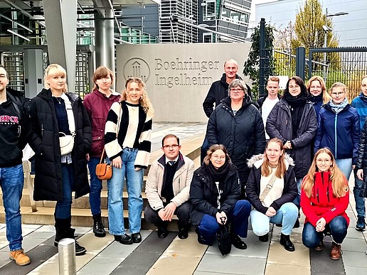 Eine Gruppe von Studierenden und Prof. Wiegert stehen vor dem Eingang der Boehringer Ingelheim RCV GmbH & Co KG und lächeln in die Kamera.