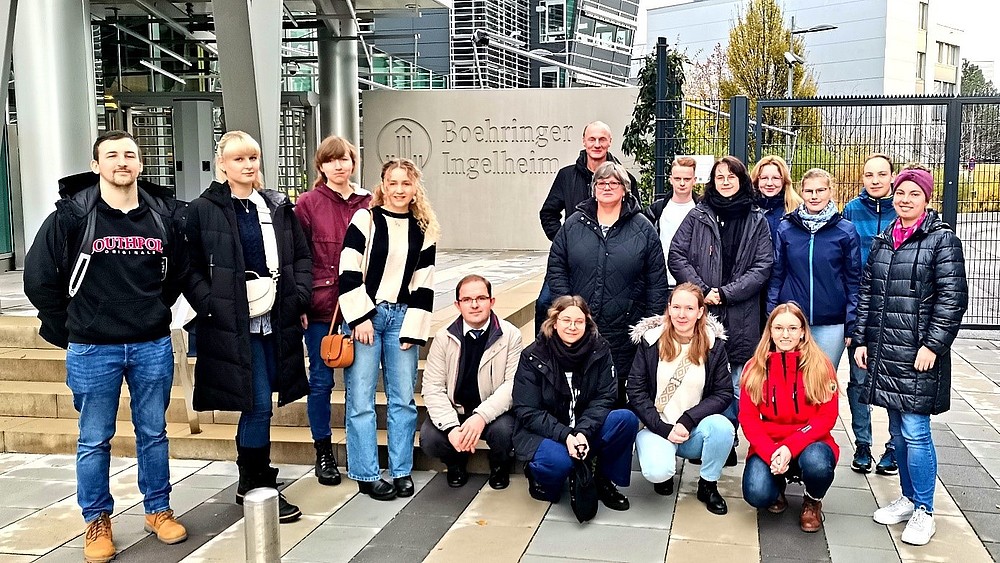 Eine Gruppe von Studierenden und Prof. Wiegert stehen vor dem Eingang der Boehringer Ingelheim RCV GmbH & Co KG und lächeln in die Kamera.