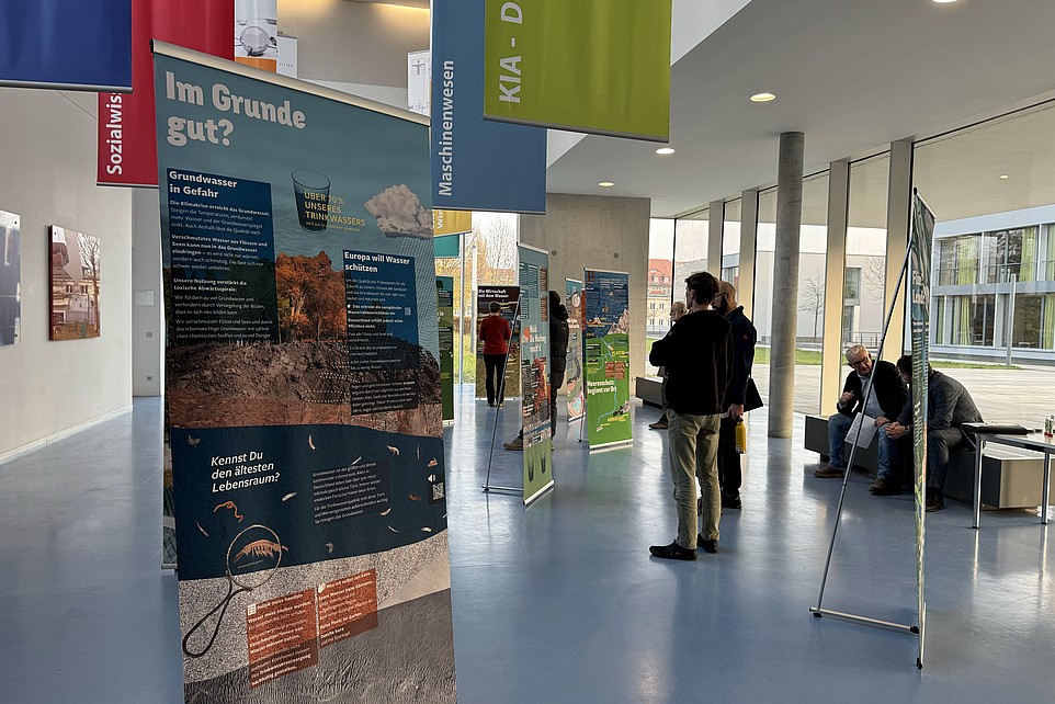 Gäste stehen im Foyer vor Ausstellungsrollups.