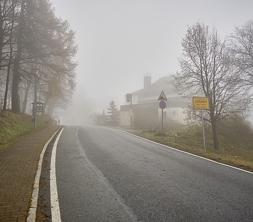 Eine Straße im Nebel, die ins Gebirge führt.