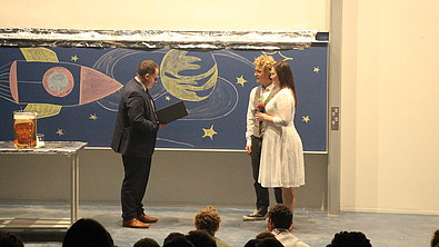Der Rektor vermählt Grace und AJ auf der Bühne.