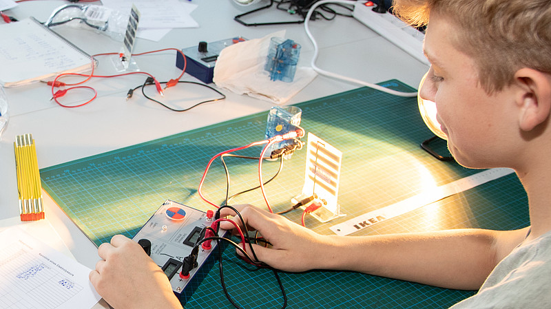 Ein Schüler sitzt am Labortisch und arbeitet mit Solarzellen.
