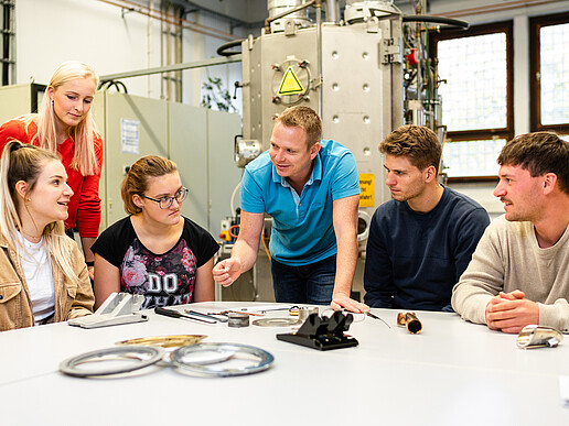 Studierende sitzen im Maschinenwesen-Labor und hören einem Lehrbeauftragten zu.